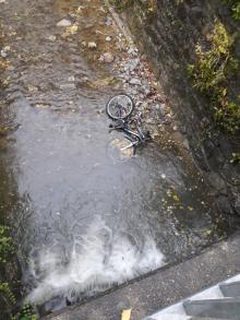 Fahrrad und Regenschirm in Bachbett